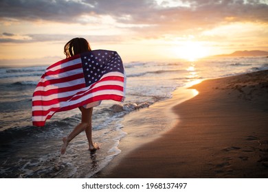 Cheerful happy woman outdoors on the beach holding USA flag having fun. - Powered by Shutterstock