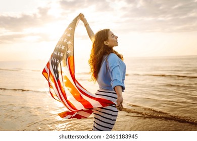 Cheerful happy woman outdoors on the beach holding USA flag having fun. USA celebrate 4th of July. Independence Day concept - Powered by Shutterstock