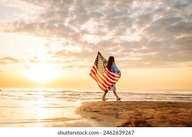 Cheerful happy woman outdoors on the beach holding USA flag having fun. USA celebrate 4th of July. Independence Day concept - Powered by Shutterstock