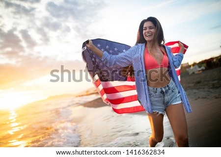 Cheerful happy woman outdoors on the beach holding USA flag having fun.