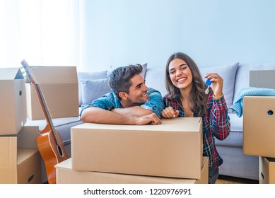 Cheerful and happy young couple holding the keys of their new home with moving cardbox during move into new apartment. Happy couple holding keys to new home. Couple celebrating moving to new home