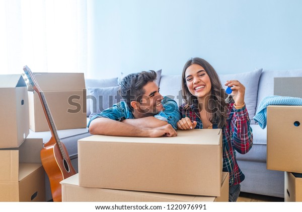Cheerful and happy young couple holding the keys of\
their new home with moving cardbox during move into new apartment.\
Happy couple holding keys to new home. Couple celebrating moving to\
new home