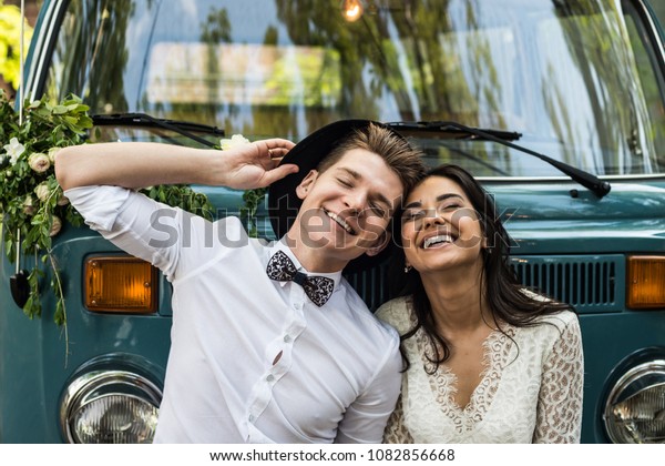 Cheerful happy young couple smiling near\
retro-minibus.\
Close-up.