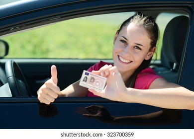 cheerful and happy young woman in her car showing her new driving license