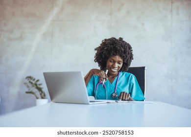 A cheerful healthcare professional wearing scrubs, working on a laptop in a modern office setting. Highlights technology use in medical fields with a relaxed and professional atmosphere. - Powered by Shutterstock