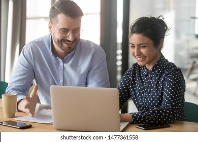 Cheerful hindu woman caucasian man multi-ethnic colleagues working together sit at desk look at computer screen discuss new project search solutions joking to increase effective communication concept - Shutterstock ID 1477361558