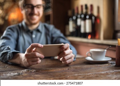 Cheerful hipster guy at the restaurant using a mobile phone, hands close up - Powered by Shutterstock