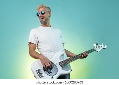 Cheerful hipster man play white bass guitar in neon lights. Rock music concept. Rock star. - Powered by Shutterstock