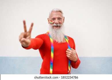 Cheerful Hipster Senior Man At Gay Pride Event Doing Peace Gesture With Hand