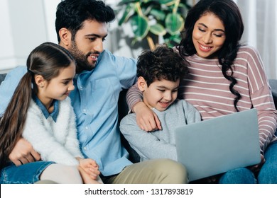 Cheerful Hispanic Family Looking At Laptop At Home