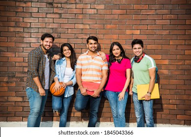 Cheerful Indian asian young group of college students or friends laughing together while sitting, standing or walking in campus - Shutterstock ID 1845043366