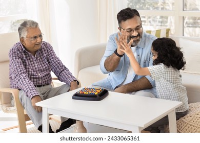 Cheerful Indian granddad and little granddaughter giving high five over board game. Happy great grandfather, grandpa and cute kid playing at home, enjoying family leisure, playtime - Powered by Shutterstock