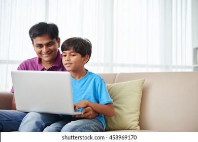 Cheerful Indian Kid And His Father Working On Laptop At Home