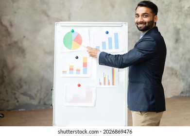 Cheerful Indian Male Tutor Teaching Students Online, Mixed-race Man Points At The Whiteboard And Looks At The Camera, Explaining, Mentor Holding Webinar