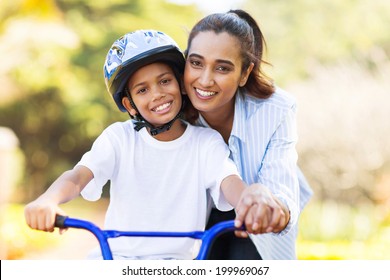 Cheerful Indian Mother Teaching Her Son To Ride A Bike