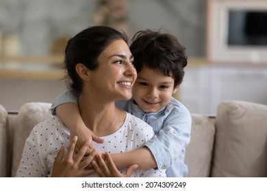 Cheerful Indian preschool kid hugging happy mom with love, gratitude, tenderness. Young mother and little son enjoying leisure time together, looking away, smiling. Family, motherhood concept - Shutterstock ID 2074309249