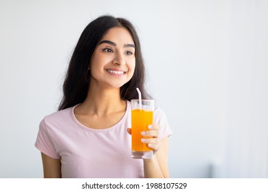 Cheerful Indian Woman Holding Glass Of Refreshing Fruit Juice Indoors, Copy Space. Joyful Asian Lady Enjoying Her Yummy Drink. Summer Detox, Wellness, Dieting Concept