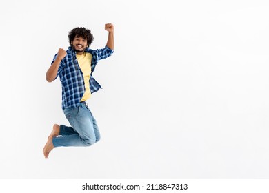 Cheerful Indian young man fun jumping on white background with copy space. Victory, celebrate triumph