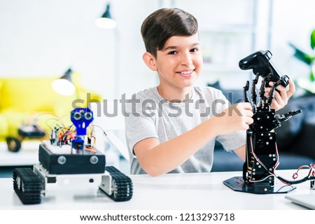 Cheerful ingenious boy holding a remote control while testing his engineering wonder