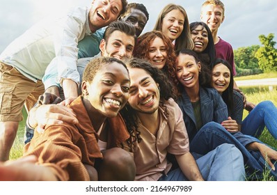 Cheerful international happy friends having fun taking selfies at picnic in the countryside - Large group of multiethnic young people smiling looking at the camera - focus on the black woman face