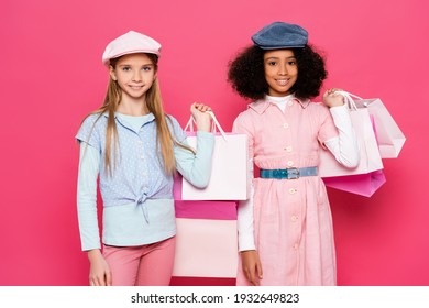 Cheerful Interracial Kids In Fashionable Clothes Posing With Shopping Bags On Pink