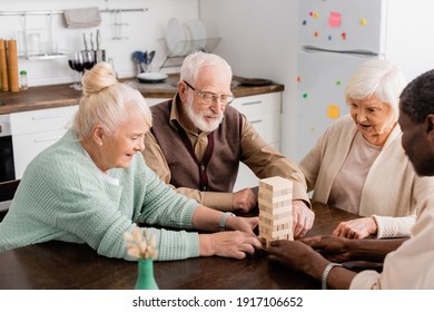 cheerful interracial pensioners smiling while playing tower wood blocks game at home - Shutterstock ID 1917106652