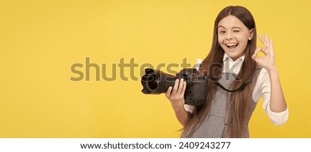 cheerful kid girl take photo with digicam show ok gesture, photography. Child photographer with camera, horizontal poster, banner with copy space.