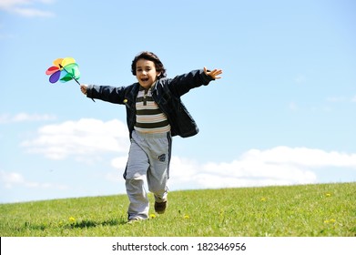 Cheerful kid having fun running on green summer meadow