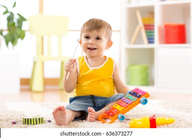 Cheerful kid little boy plays musical toys