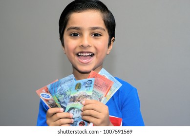 Cheerful Kid With Money. Australian Dollars In Hands Of Happy Child Looking At Camera. Excited Child With Australian Money. Indian Child, Australian Currency. Concept Of Happy Kid Getting Pocket Money