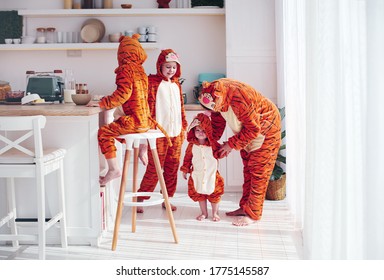 cheerful kids with mother in kigurumi pajamas having fun in the morning on the kitchen