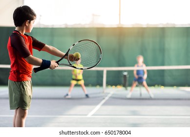 Cheerful kids playing tennis on court