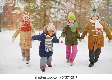 Cheerful kids running in snow in park