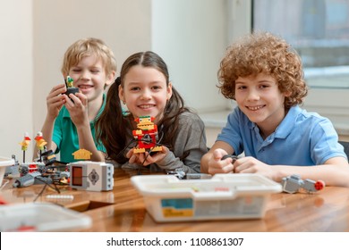 Cheerful Kids Showing Their Creations Made Of Plastic Blocks. Hands-on Activities For STEM Classes.