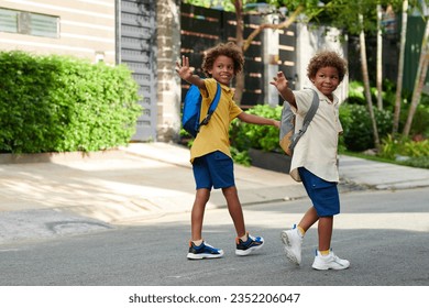 Cheerful kids waving their parents when leaving house and walking to school - Powered by Shutterstock