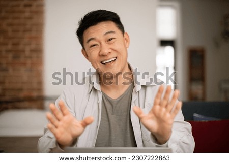 Cheerful korean man having virtual online meeting and emotional conversation, gesturing to camera during video call, working remotely from home, webcam view