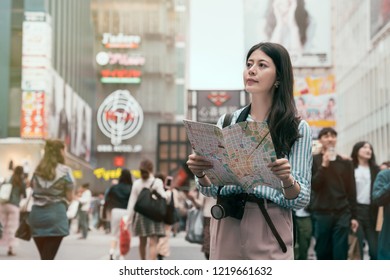 Cheerful Lady Searching Direction On Location Map While Traveling Abroad In Japan. Young Traveler Standing In The Shopping Center. Asia Travel Vacation In Japan.