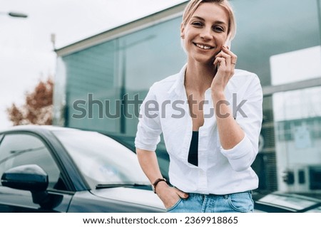 Cheerful lady smiling and looking at camera while talking on phone