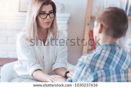 Cheerful lady smiling while looking at a teenage kid and trying to establish contact and trust with a young patient. Stock photo © 
