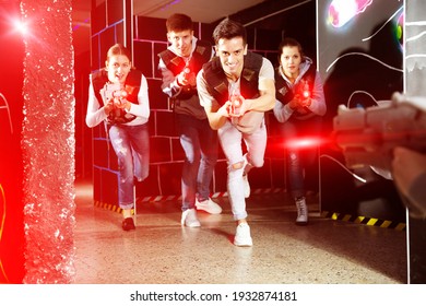 Cheerful Laser tag players young mens and womens playing in teams in dark laser tag station. High quality photo