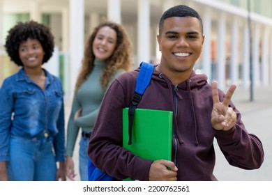 Cheerful Latin American Male Student With Backpack And Group Of International Students Outdoor In Summer In City