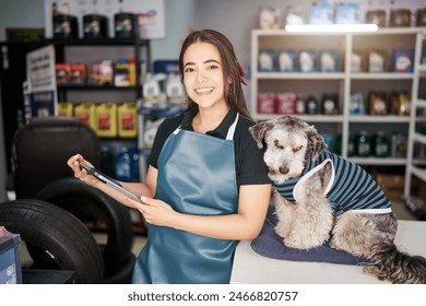 cheerful latin american saleswoman entrepreneur holding a tablet next to pet in a small auto parts supply shop - Powered by Shutterstock