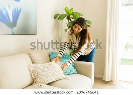 Cheerful latin young woman at her cozy home cleaning and tidying up her house smiling looking at her beautiful cozy living room