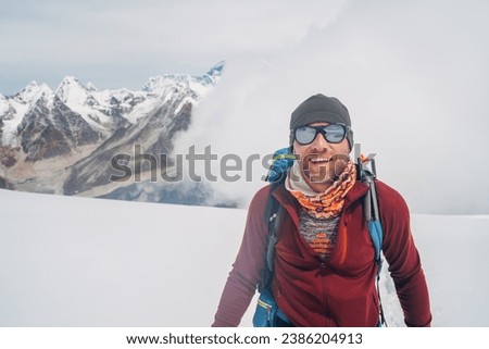 Cheerful laughing climber in sunglasses portrait with backpack ascending Mera peak high slopes at 6000m enjoying legendary Mount Everest, Nuptse, Lhotse with South Face wall beautiful High Himalayas.