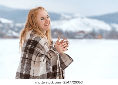 Cheerful laughing ginger hair young woman with cup of hot tea in her hands against winter landscape - Powered by Shutterstock