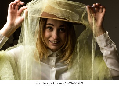 Cheerful Laughing Girl With Brown Hat Wrapped In Tulle On A Dark Background