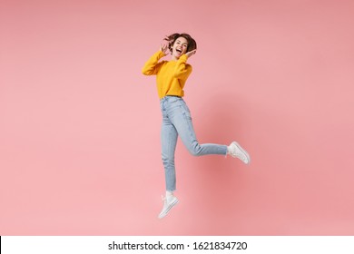 Cheerful Laughing Young Brunette Woman Girl In Yellow Sweater Posing Isolated On Pastel Pink Wall Background In Studio. People Lifestyle Concept. Mock Up Copy Space. Having Fun Fooling Around Jumping