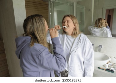 Cheerful Lesbian couple brushing teeth together in bathroom - Powered by Shutterstock