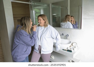 Cheerful Lesbian couple brushing teeth together in bathroom - Powered by Shutterstock