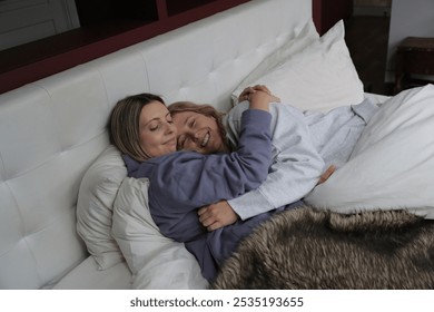 Cheerful lesbian couple embracing in bed - Powered by Shutterstock